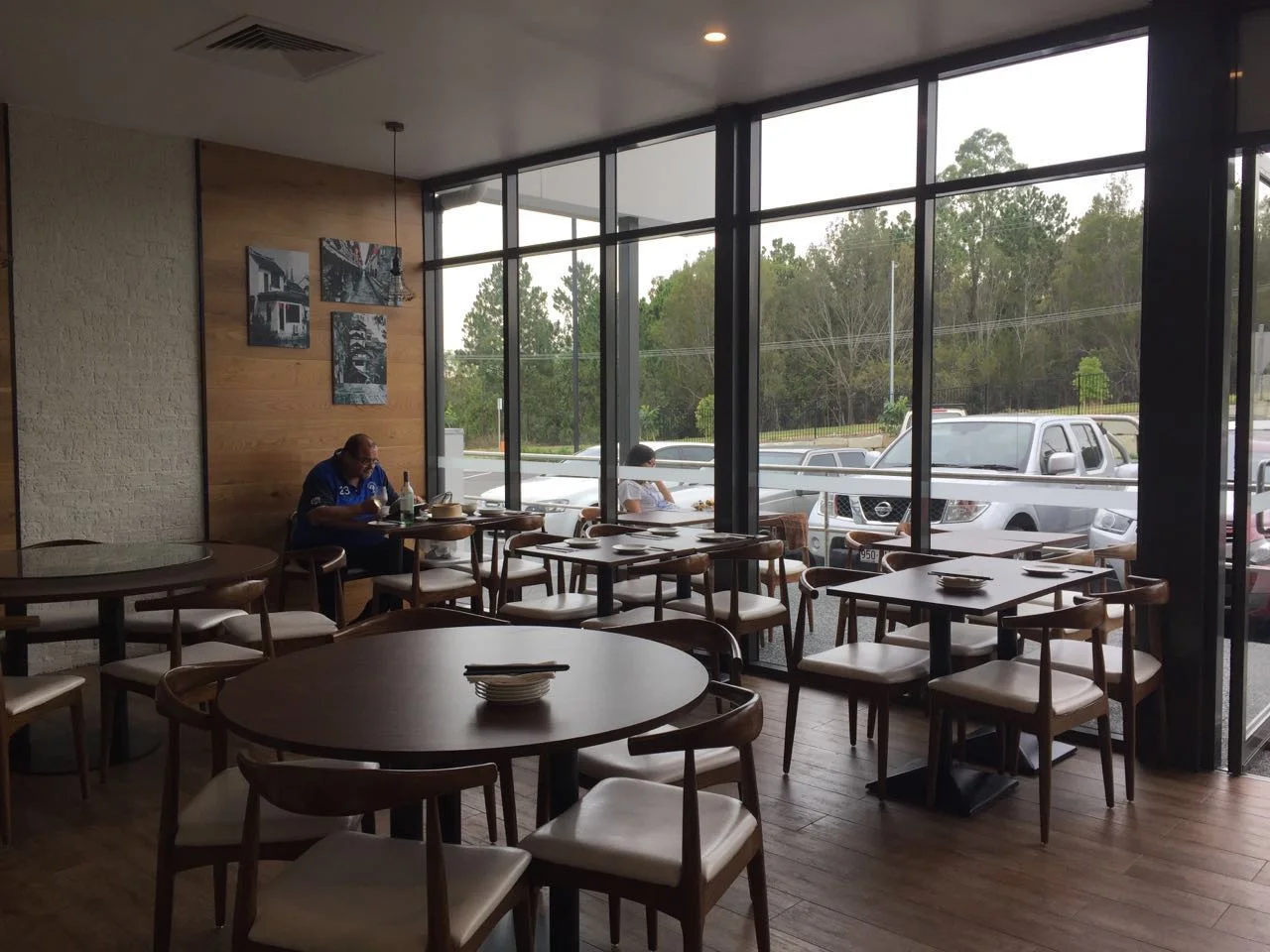 Dark wood-tone curved-back restaurant chairs with cream seats around round and rectangular tables in a LONGG US project