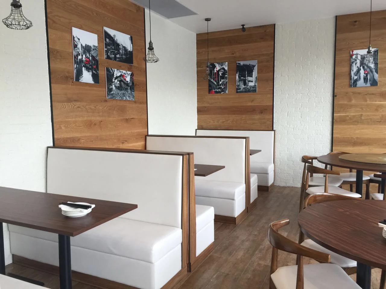 Cream high-back restaurant booths with dark framing and rectangular tables in a LONGG US project
